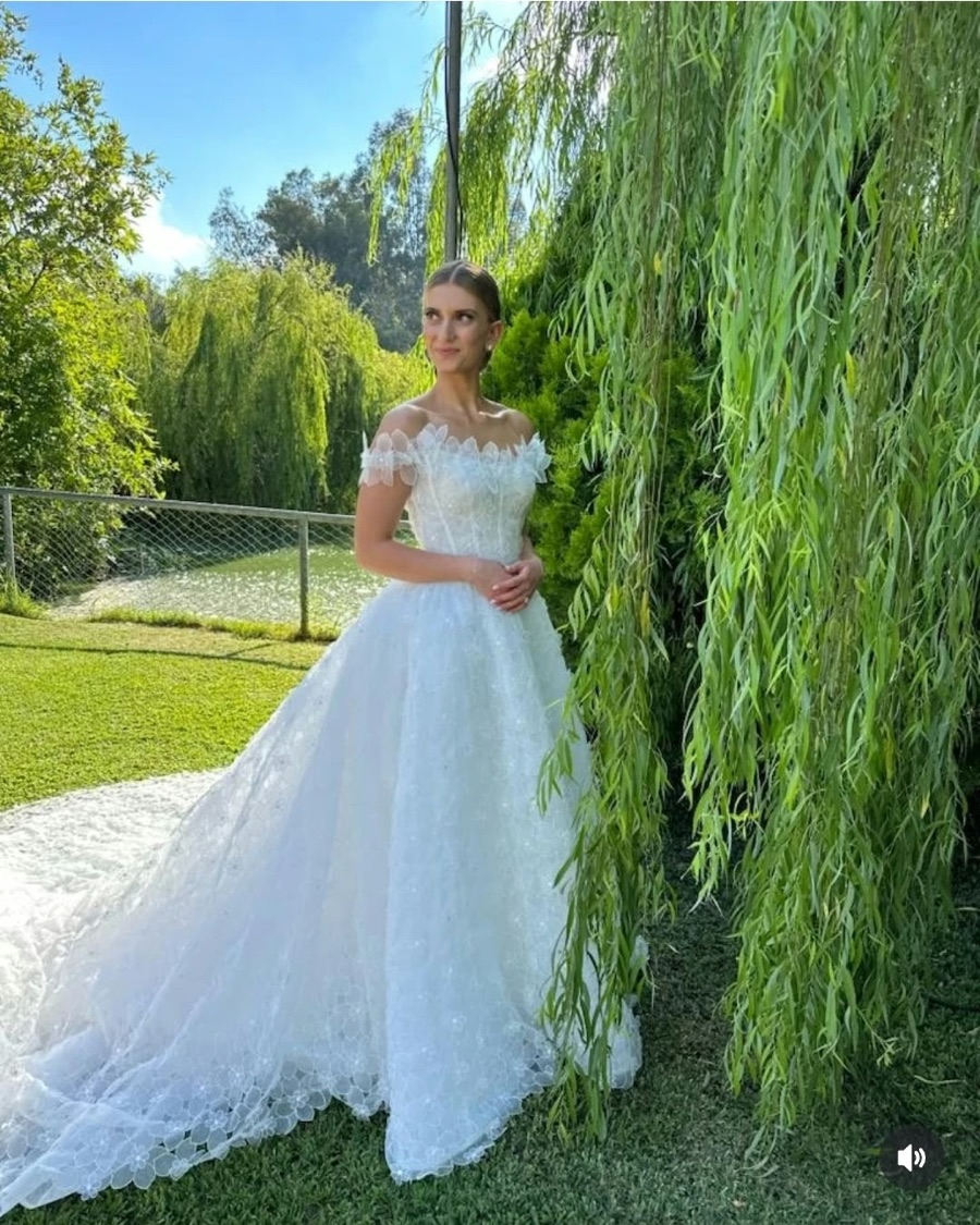 Bride in a white gown beside a willow tree